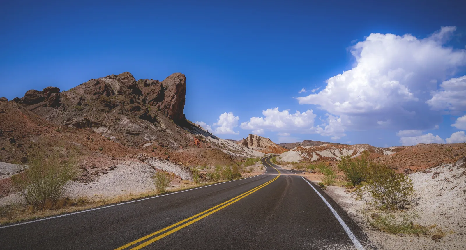 A paved two-lane road curving between desert hills and rock outcrops in Big Bend National Park, Texas