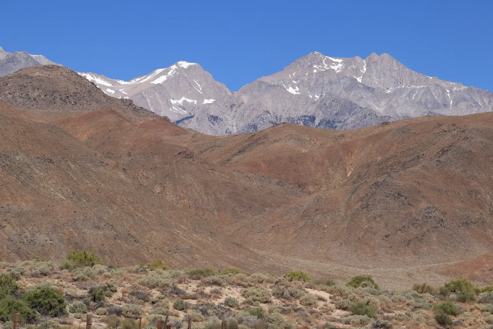 Snow-streaked granite peaks above brown foothills and sagebrush near Lone Pine, California, under a clear blue sky