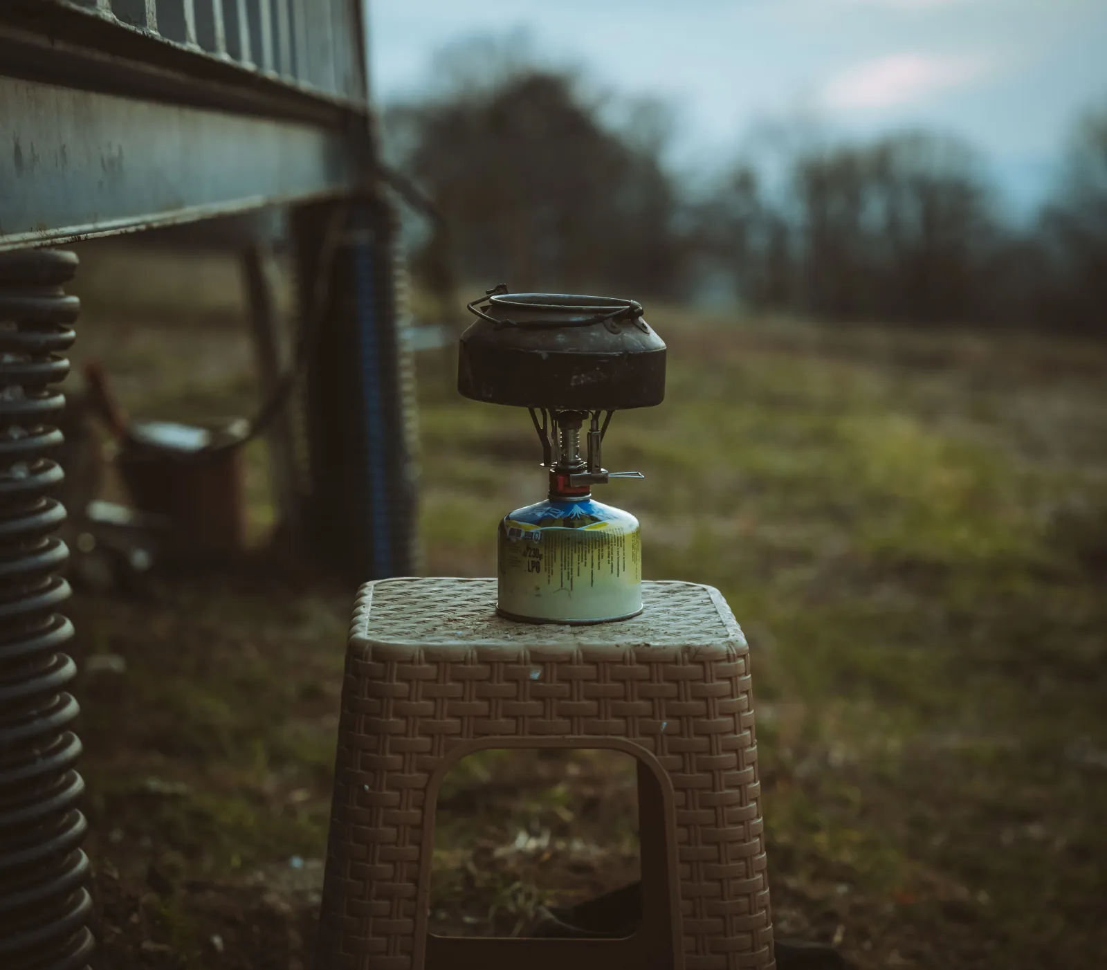 A small portable camp stove burner set up outdoors in an open field