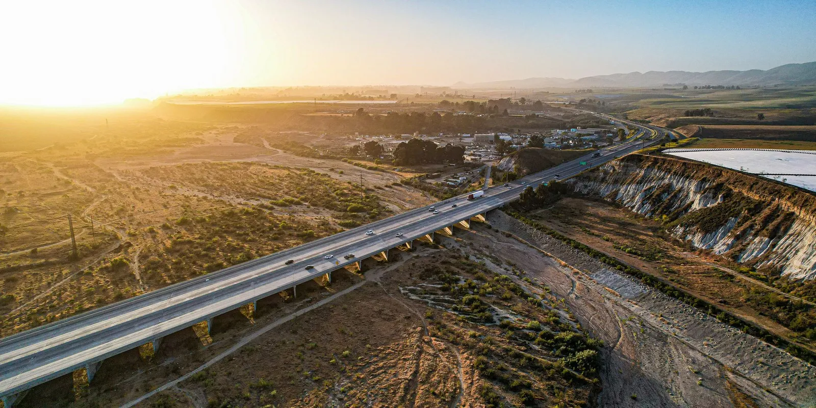 A divided highway crossing dry brown farmland near Santa Maria, California, at sunset