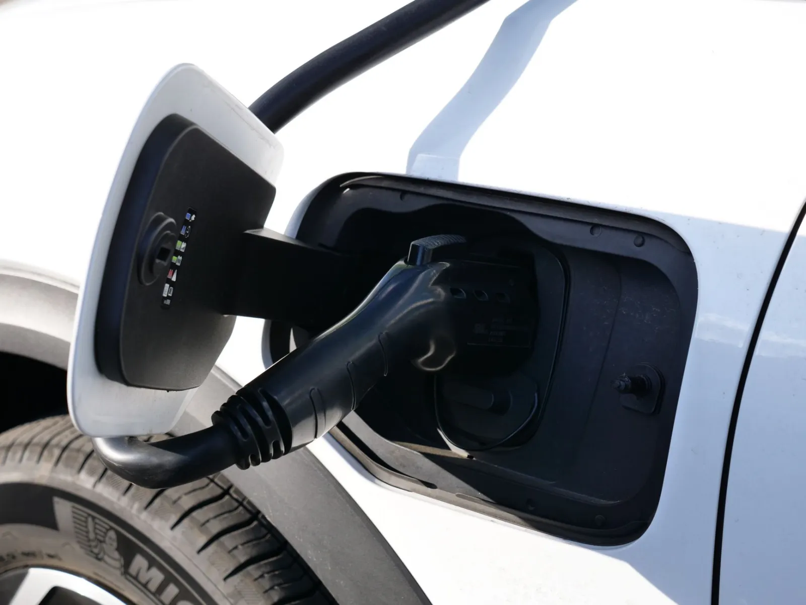 Close up of a charging cable connected to the charge port of an electric car