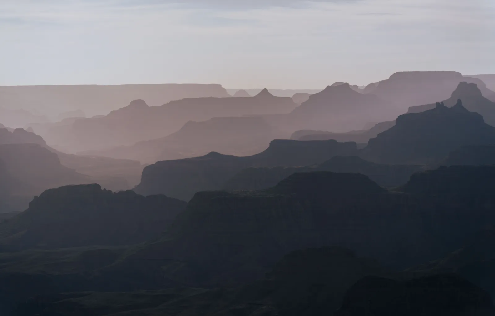 Canyon rim at dusk with layered rock walls receding into haze