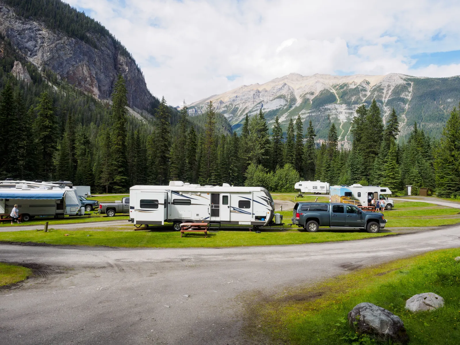 Trailers and pickups at a developed mountain campground with picnic tables and a loop road