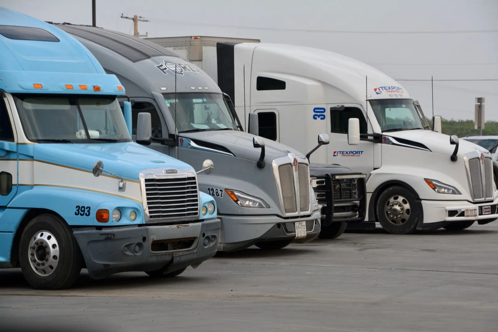 A row of semi trucks parked front-on in a paved lot in Texas
