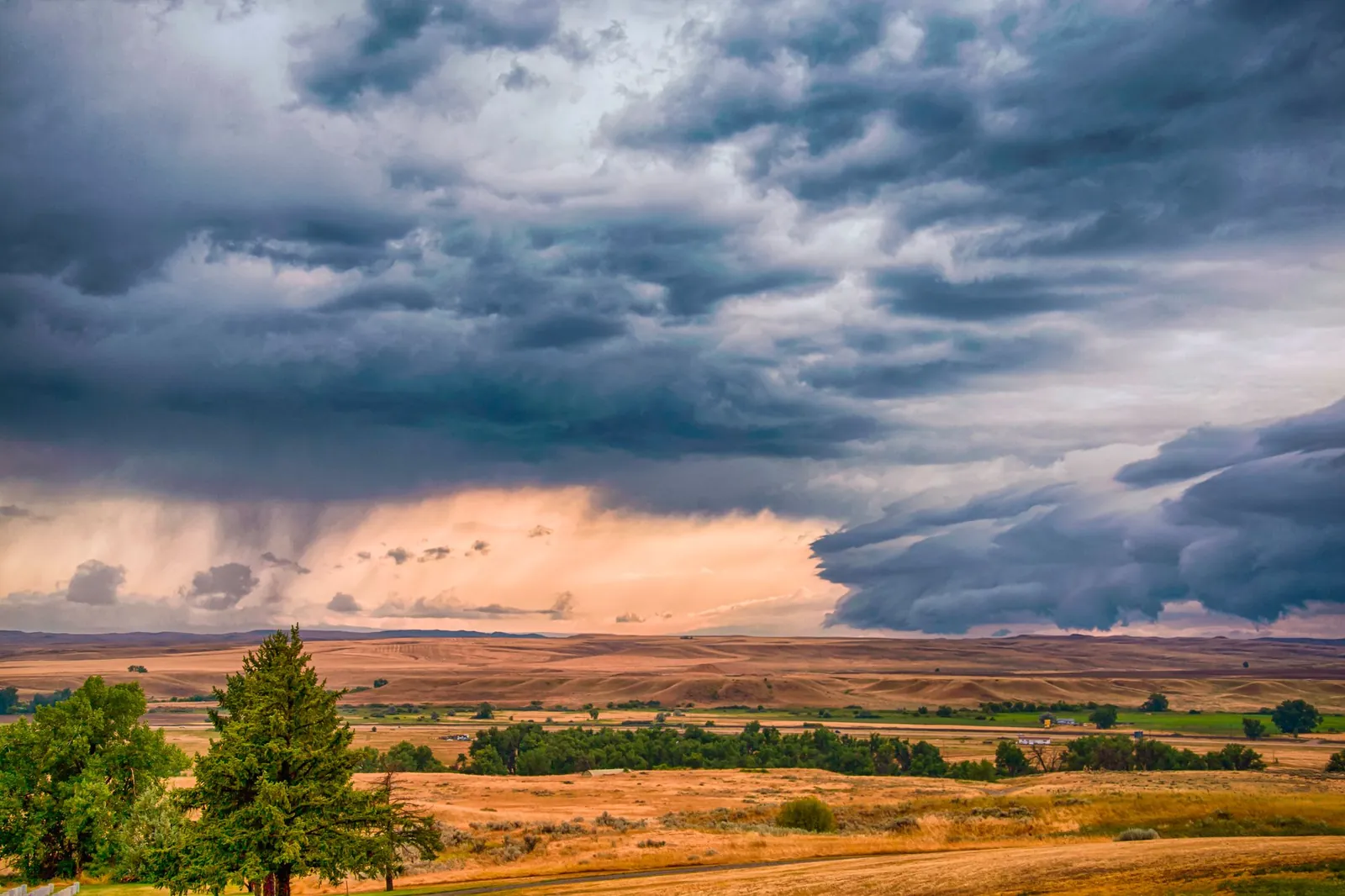 Storm clouds building over rolling dry grassland and low hills in Montana