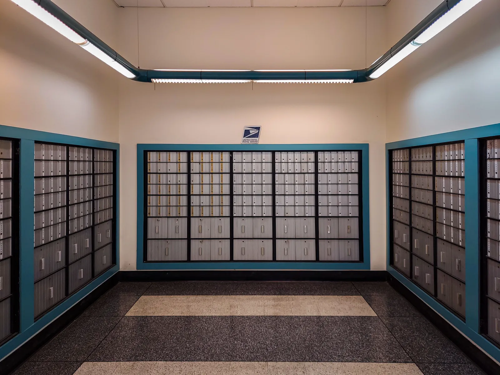 Rows of numbered post office boxes lining the walls of a post office lobby